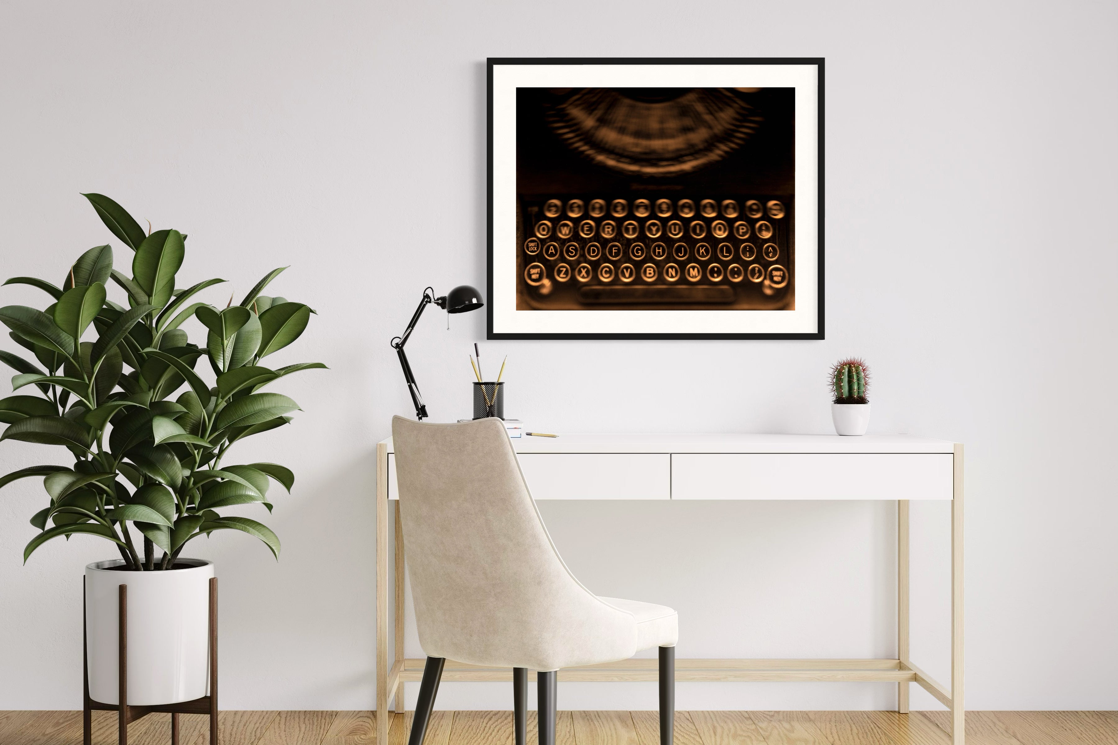 close up of old typewriter from above, horizontal black and white photo in black frame with white matte on white wall above modern desk with plant on the left, hardwood floors, white desk and chair