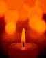 close up photo of single candle with other candles out of focus in the background 