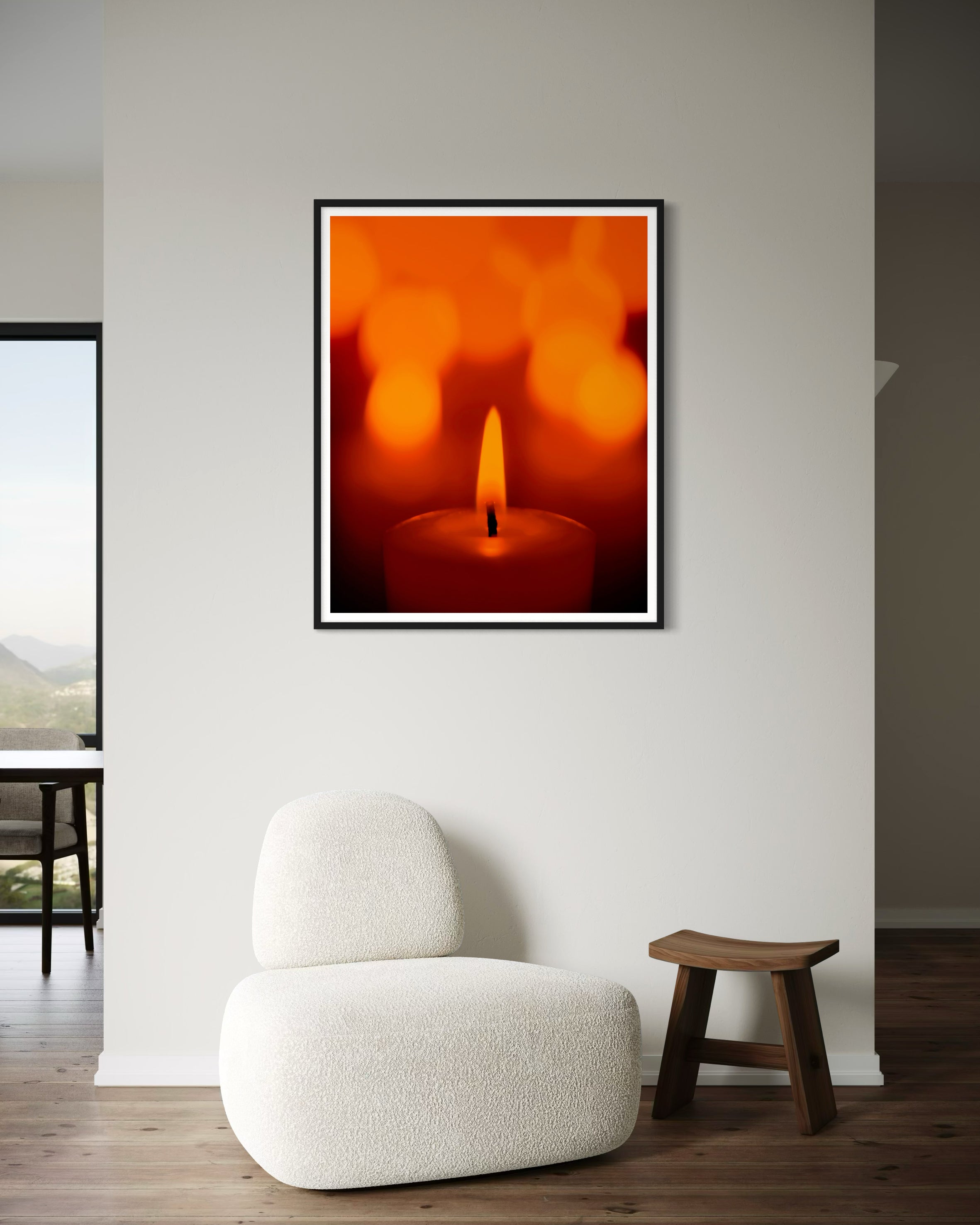 close up photo of single candle with other candles out of focus in the background in black frame with white matte on tan wall in minimalist home