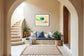 photo of abstract purple, green, blue, yellow wave at the bottom on orange overall in black frame with white matte tan wall in Mediterranean style sitting area with earth tones