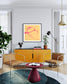 Modern living room with yellow cabinet, brown chairs, and abstract art on the wall.