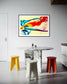 swirls of blue, yellow, orange, teal, purple and red on light yellow background in black frame with off white matte on light gray wall in modern kitchen