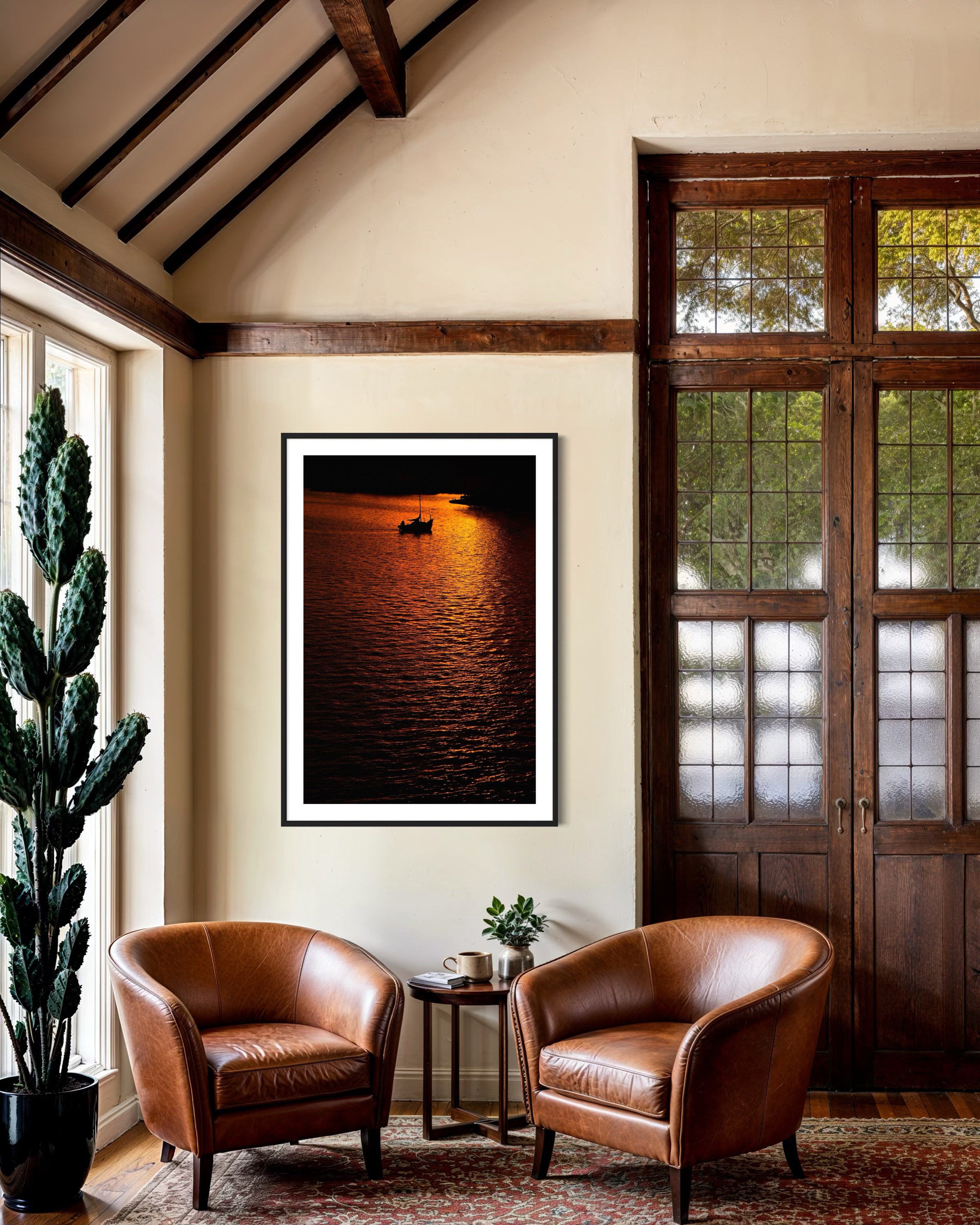 Two brown leather chairs in a room with a large framed photograph of a sunset over water on the wall.