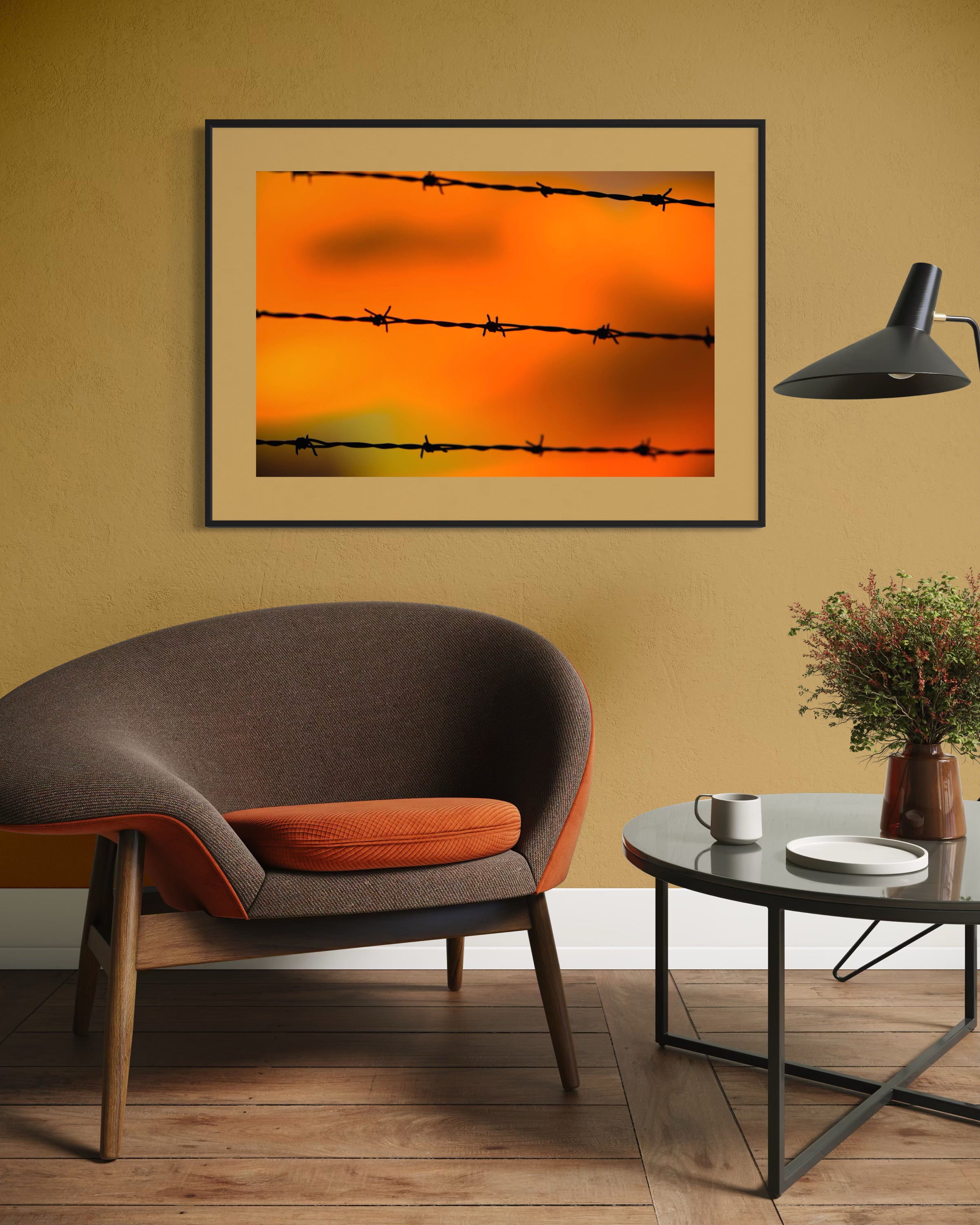 Framed artwork of barbed wire against an orange sky in a living room setting.