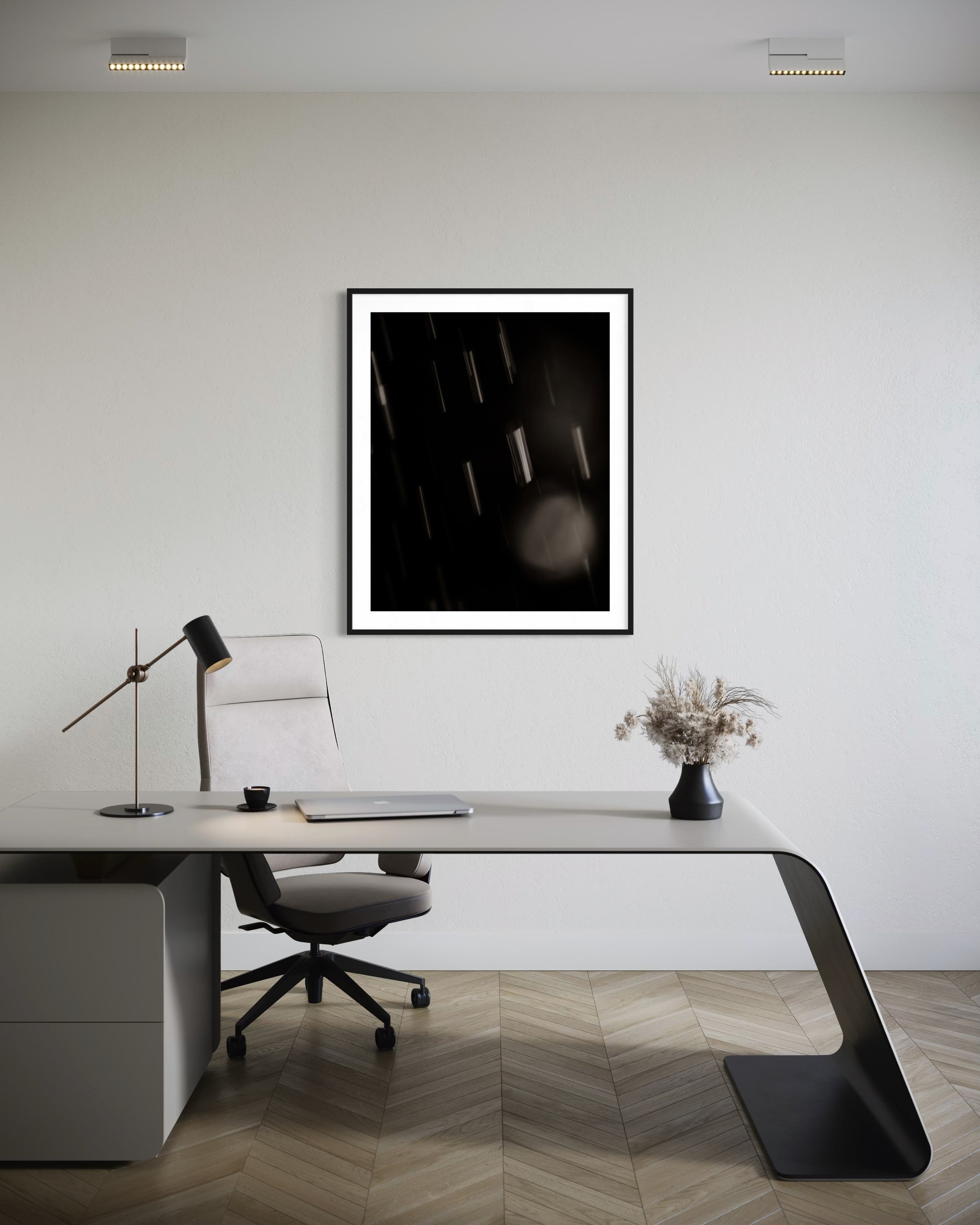 Modern office desk with a chair, lamp, and framed artwork on a white wall.