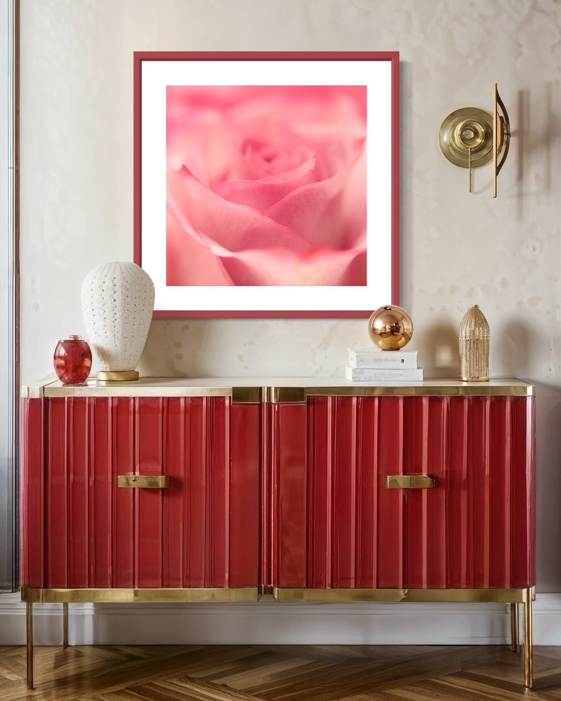 macro of pink rose shot in studio with shallow depth of field in pink frame with light pink matte on light tan wall above red piece of furniture with gold trim
