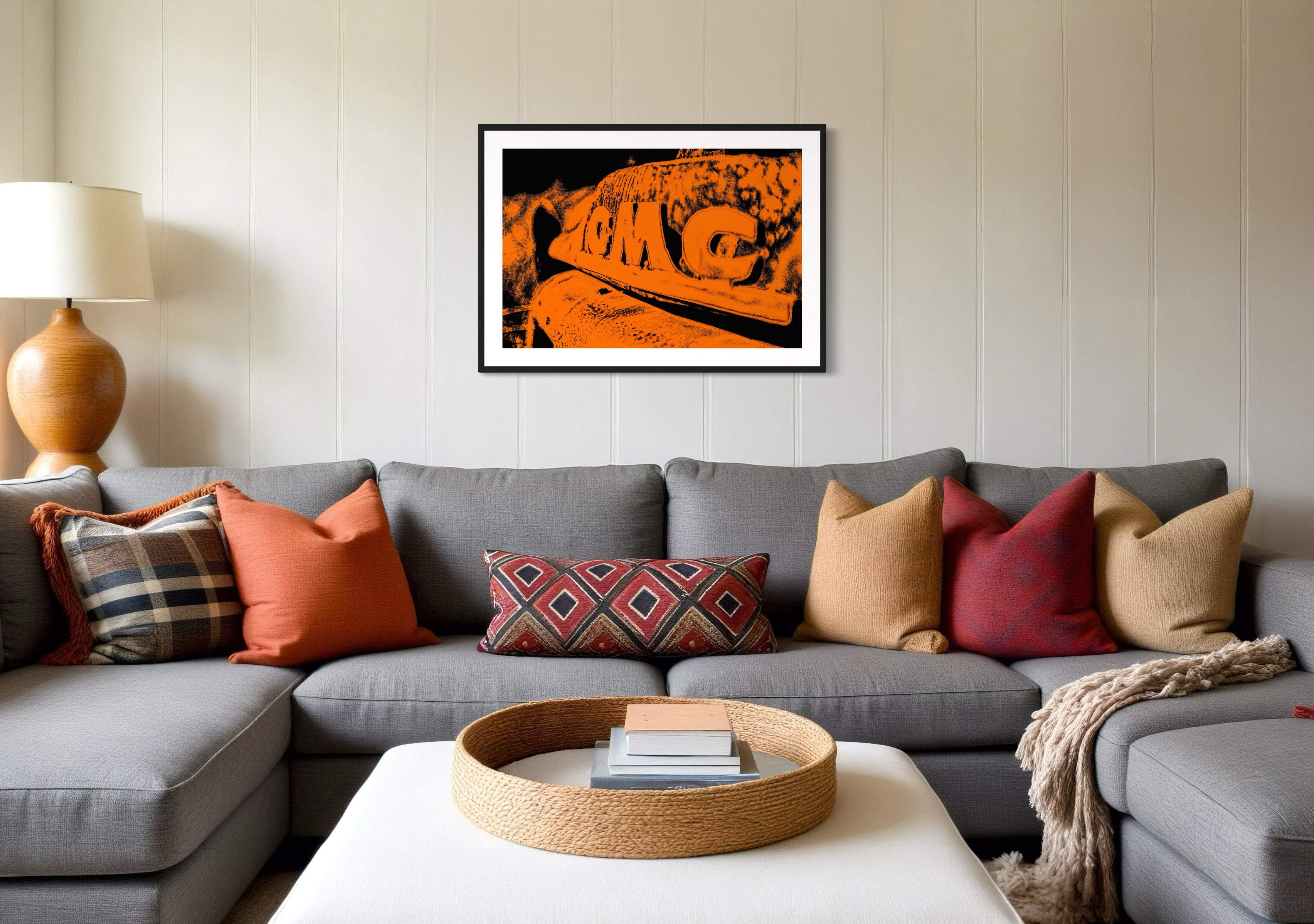 orange tone photo of front of old truck in black frame with white matte on tan wall in modern living room gray couch and lots of throw pillows