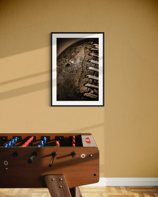 Framed picture of a piano on a beige wall with a foosball table in the foreground.