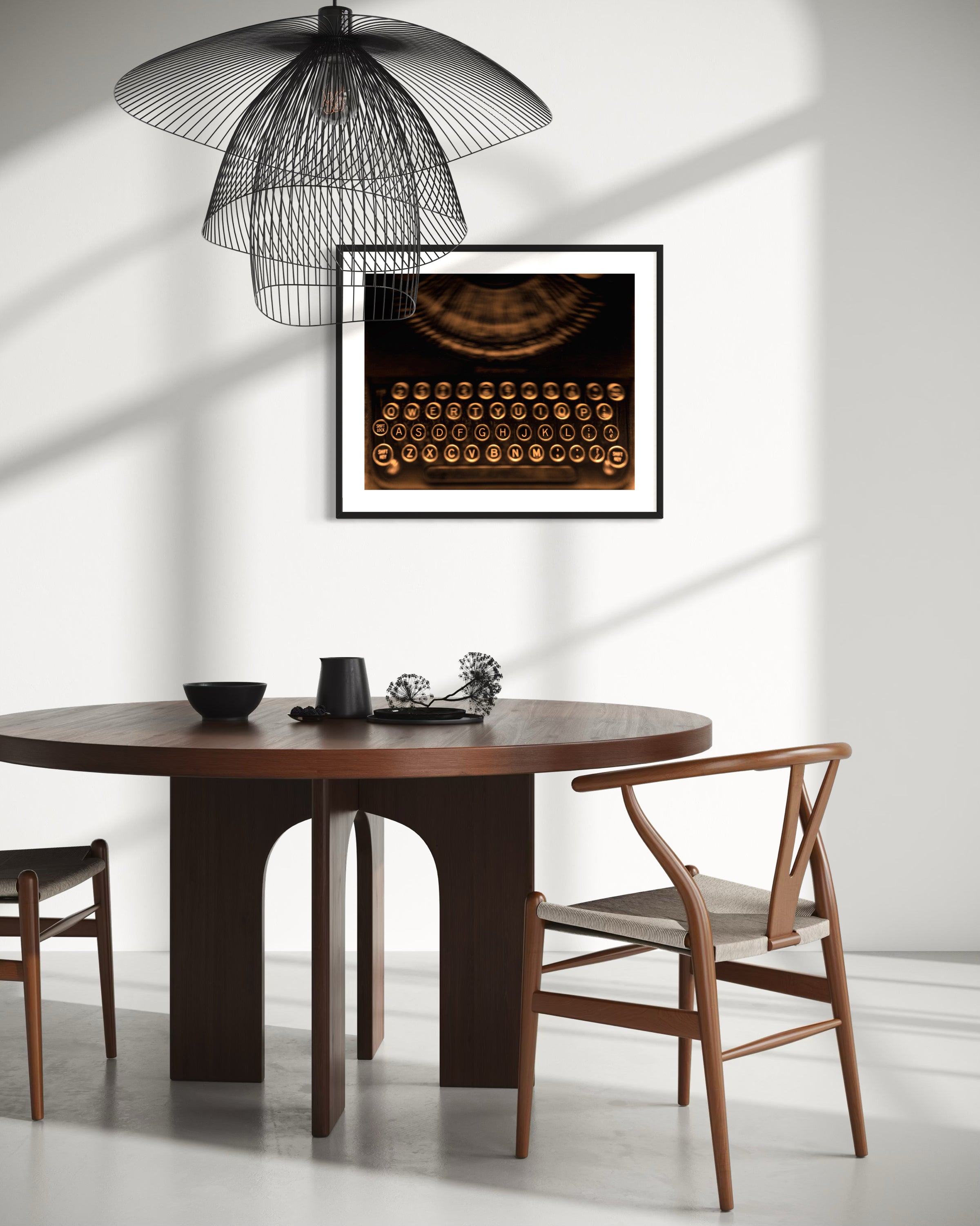 close up of old typewriter from above, horizontal black and white photo in black frame with white matte on white wall with dramatic shadows in modern breakfast room with wooden table and chairs