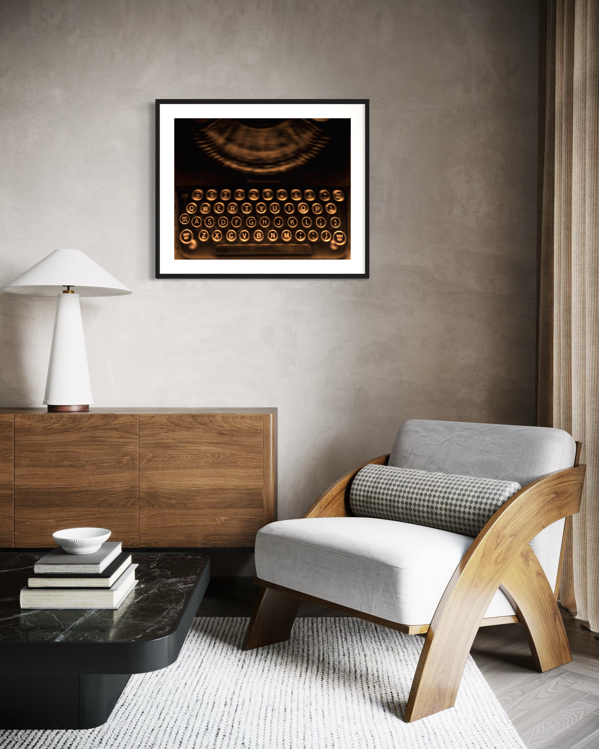 close up of old typewriter from above, horizontal black and white photo in black frame with white matte on tan wall in modern sitting area with white chair and black coffee table