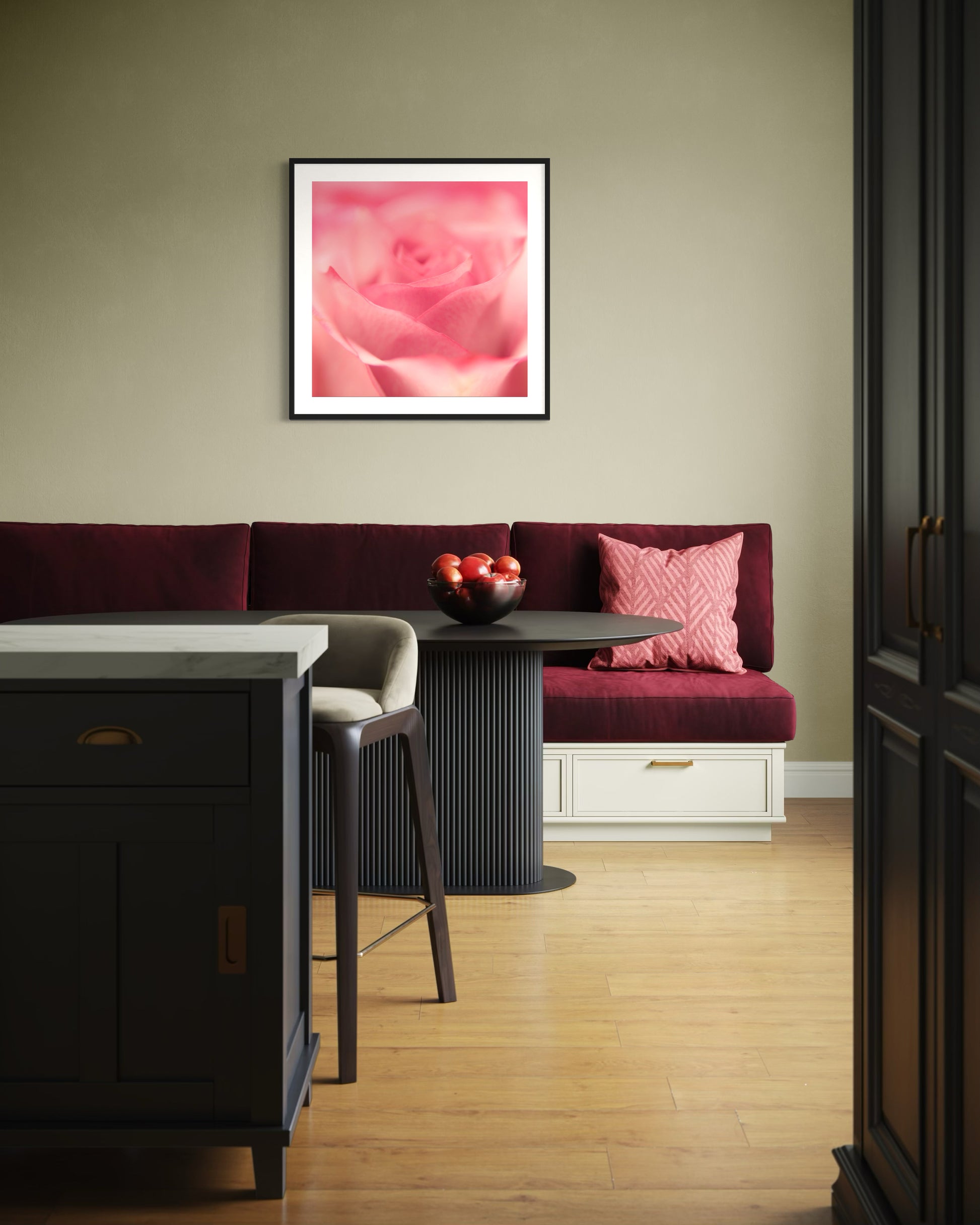 macro of pink rose shot in studio with shallow depth of field in black frame with white matte on tan wall above long bench with burgundy cushions