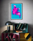 bright pop art photo of pink lily on blue background in black frame with white matte on light gray wall above small funky multicolored stacked shelves with small lamp