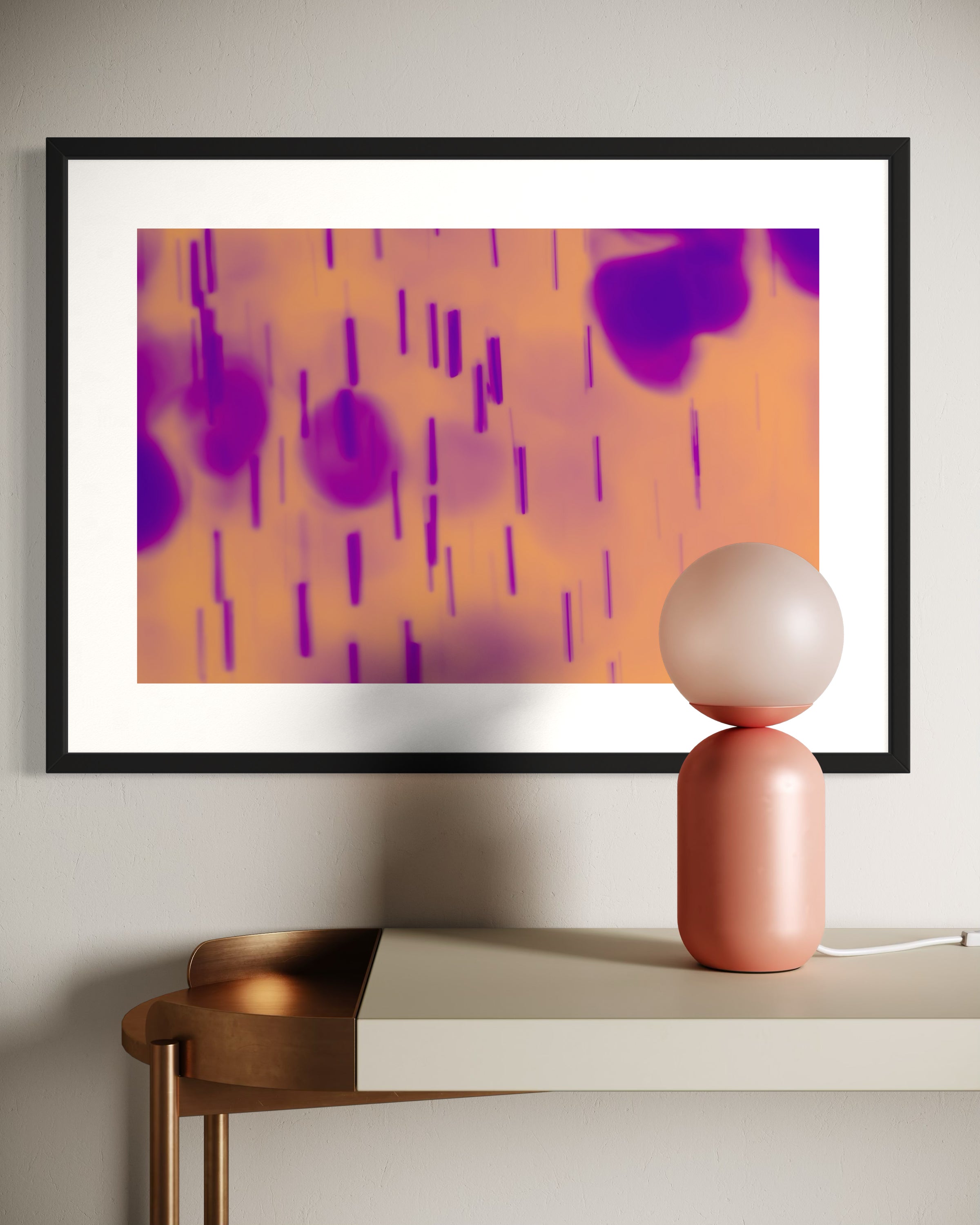 blurred rain in purple on pale yellow background in black frame with white matte on tan wall above white and gold piece of furniture with funky oval lamp on top