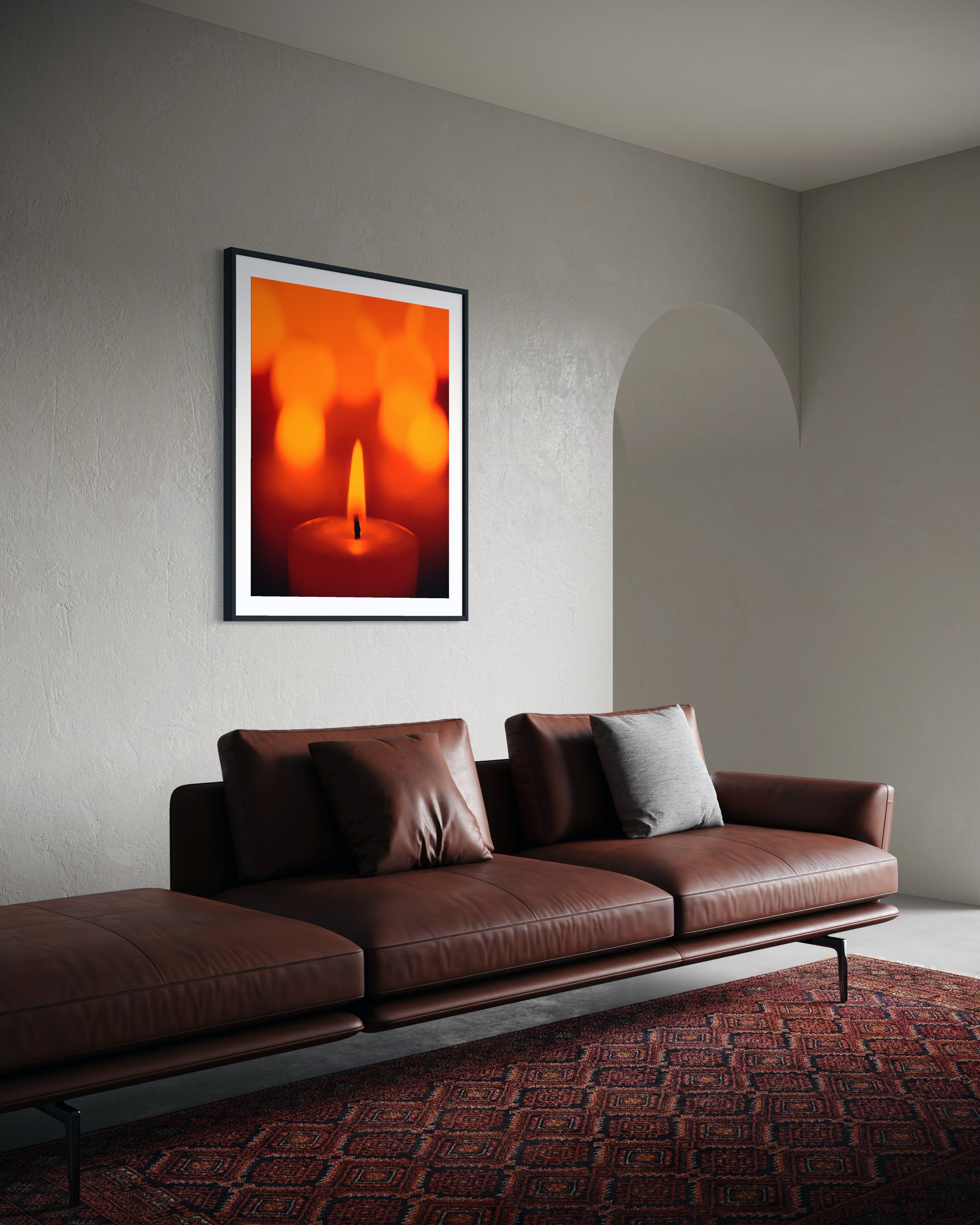 close up photo of single candle with other candles out of focus in the background in black frame with white matte on off white wall in minimalist living room with brown leather couch