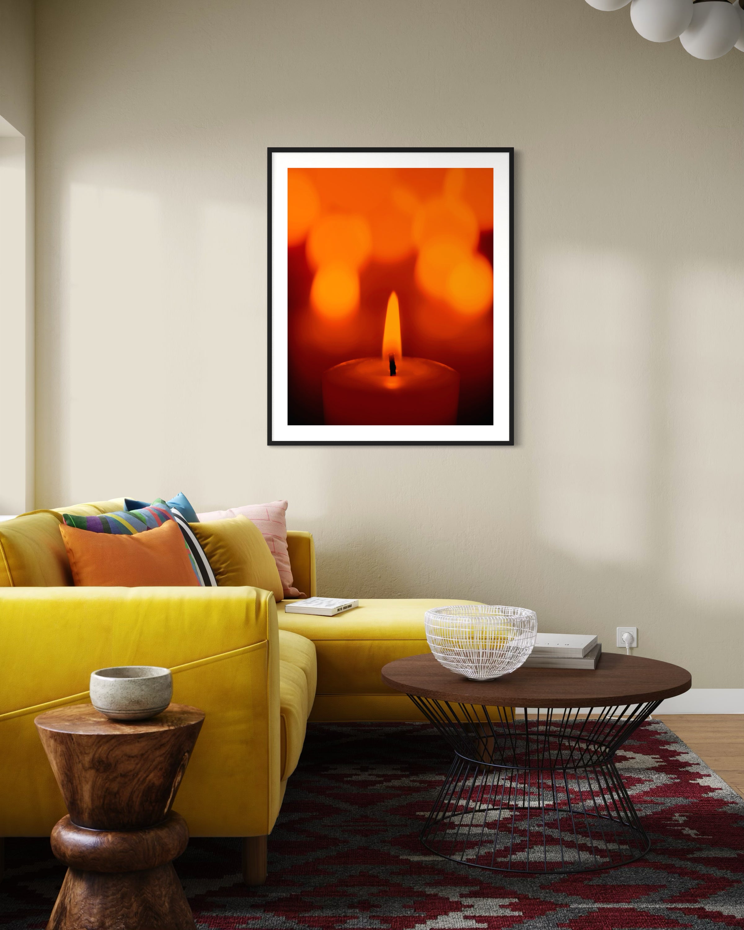 close up photo of single candle with other candles out of focus in the background in black frame with white matte on light tan wall in modern living room with bright yellow couch