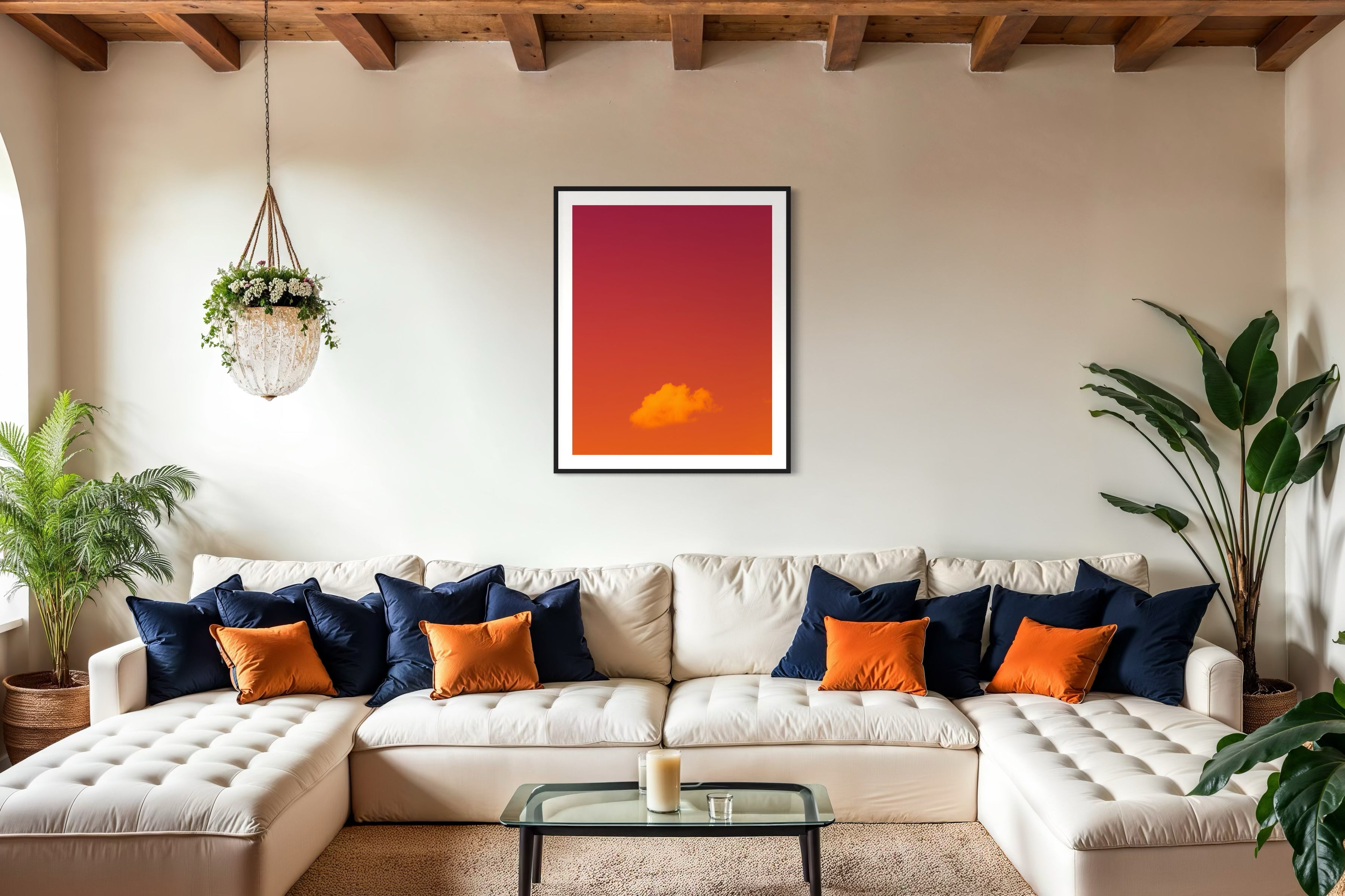 warm tone photo of single cloud in black frame with white matte on white wall above white couch in country style living room with exposed beams in the ceiling