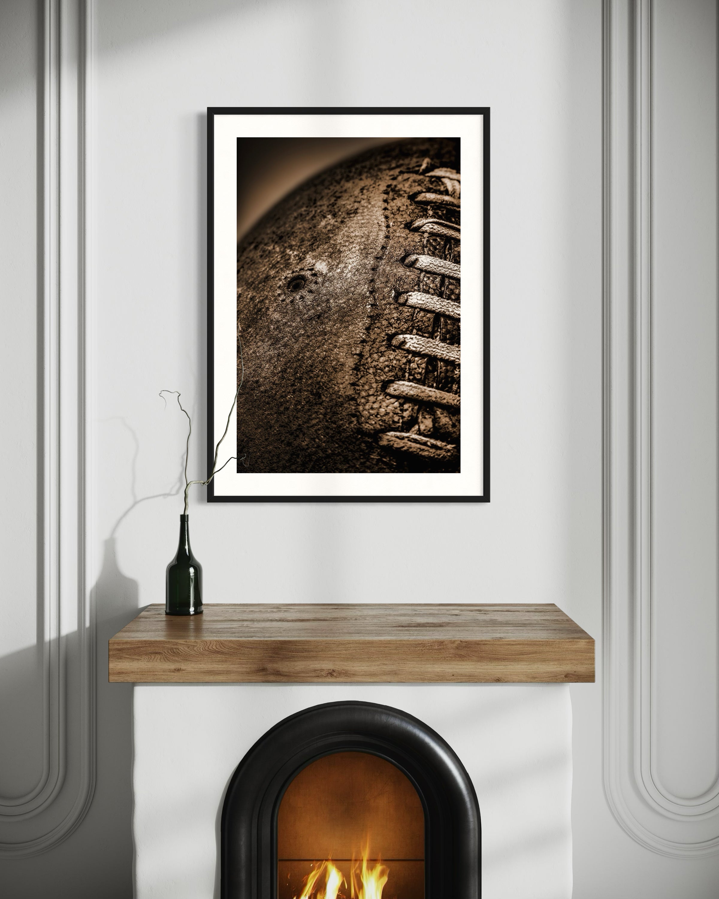 Sepia tone old football close up with a grungy look shot in studio in black frame with white matte on white wall above small arched fireplace