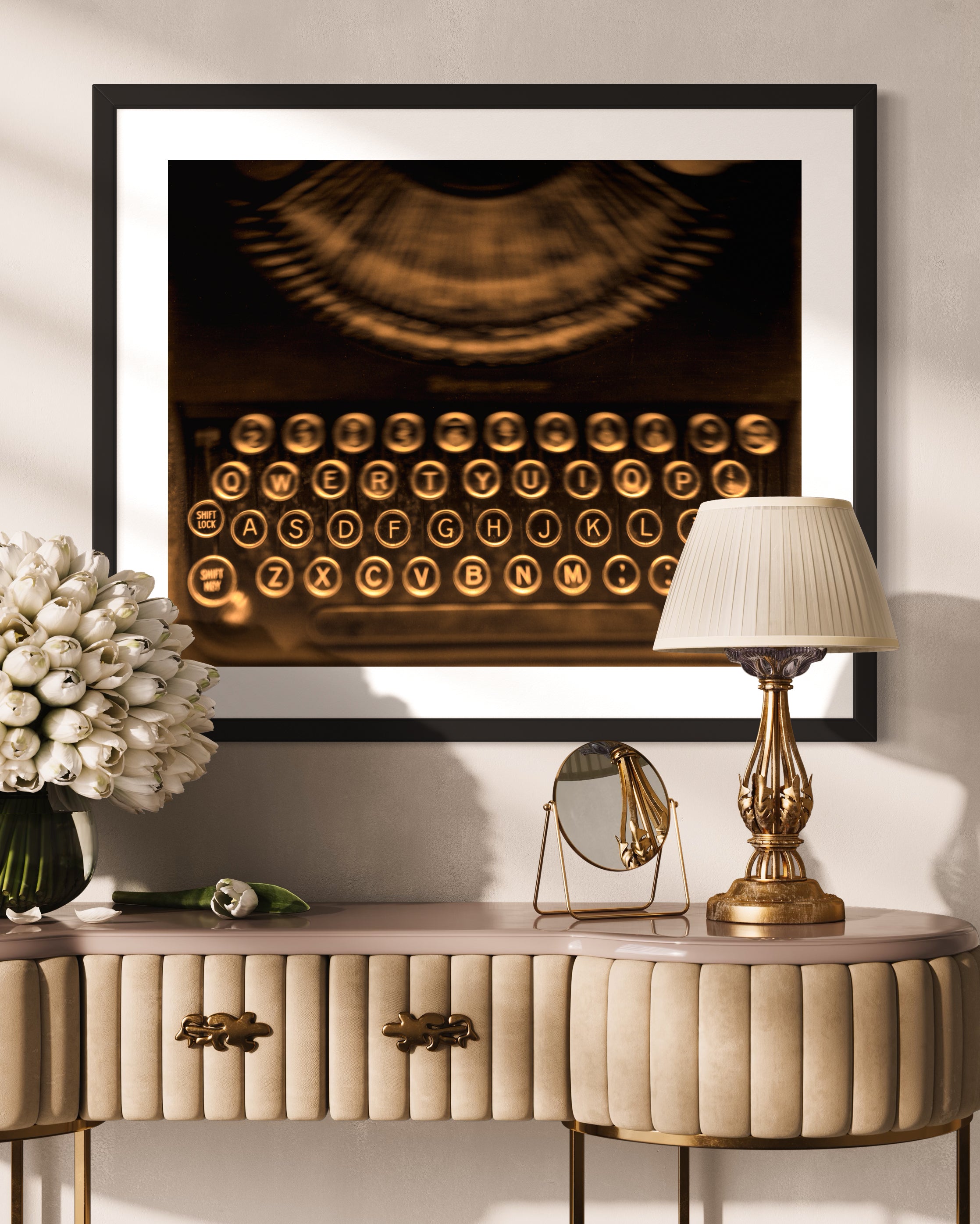 close up of old typewriter from above, horizontal black and white photo on light tan wall slightly above upscale table with lamp and flowers